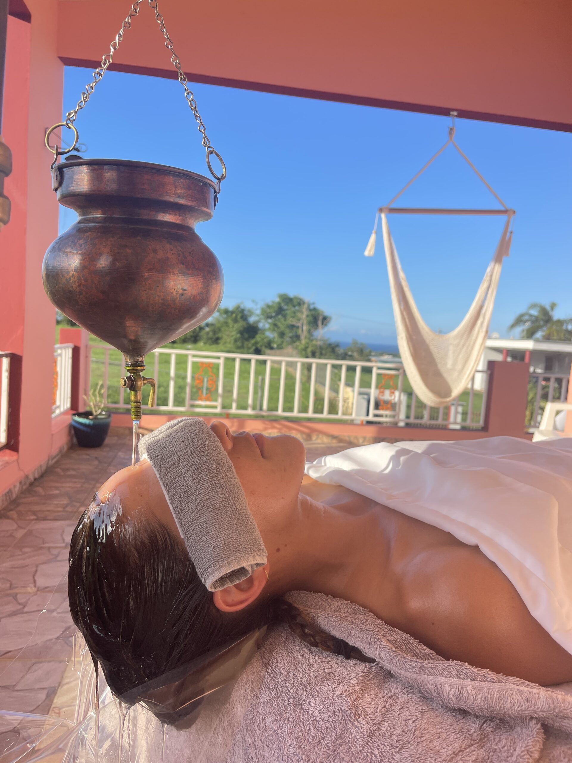 A guest receiving shirodhara therapy outdoors