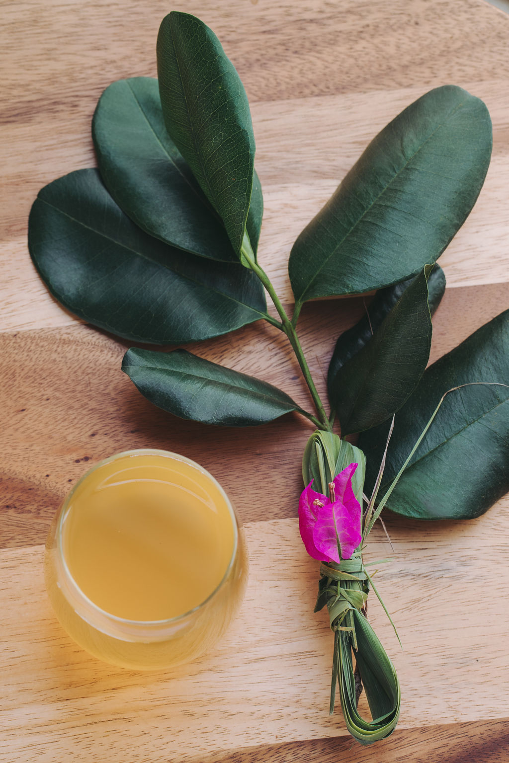 A fresh herbal decoction beside a bundle of leaves and lemongrass